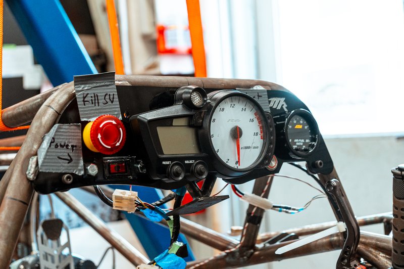 Formula SAE dashboard cluster showing the kill switch, tachometer, and air/fuel ratio gauge wired into the car's roll hoop